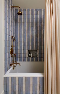 a bath tub sitting under a window next to a shower faucet in a bathroom