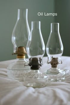 three glass oil lamps sitting on top of a bed