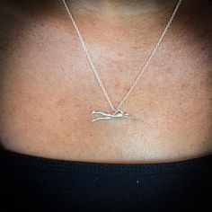 a woman wearing a silver necklace with a bird on it's back and the word love