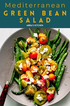 green bean salad with tomatoes and feta cheese in a gray bowl on a white table