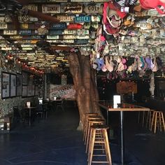 there are many pairs of shoes hanging from the ceiling in this restaurant with tables and stools