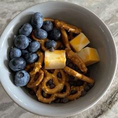 a bowl filled with blueberries, bananas and pretzels