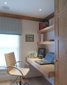 a laptop computer sitting on top of a wooden desk next to a chair and window