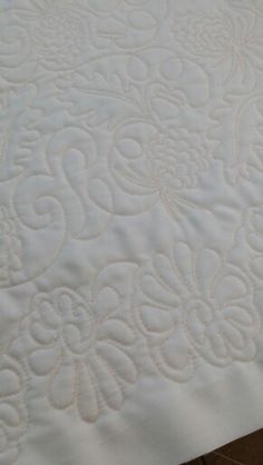 a close up view of a white quilted bed sheet with an intricate design on it