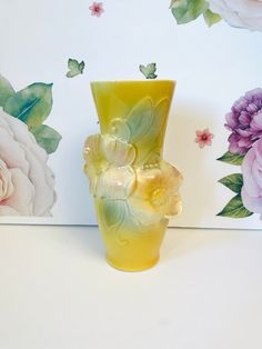 a yellow vase with flowers painted on it