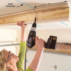 a woman is using a driller on the ceiling