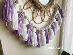 a purple and white tasseled necklace hangs on the wall next to a mirror