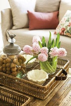 two wicker trays with flowers and nuts in them sitting on a coffee table