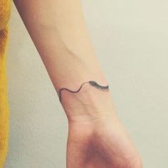 a woman's arm with a small black wave tattoo on it