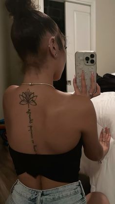 a woman with a tattoo on her back taking a selfie