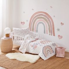 a child's bedroom with a rainbow wall decal on the wall and bedding