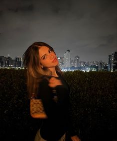 a woman standing on top of a lush green field next to a tall building at night