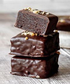 three pieces of chocolate fudge cake stacked on top of each other, with nuts in the middle