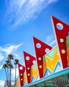 colorfully painted carnival rides with palm trees in the background and blue sky above them