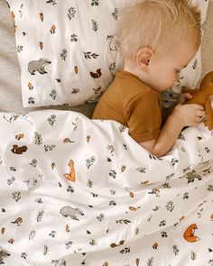 a little boy laying in bed with a stuffed animal