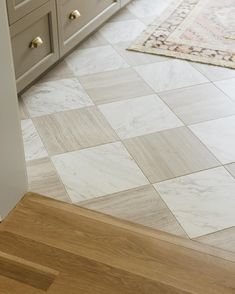 a kitchen floor with white and brown tile on the bottom, wood stairs leading up to it