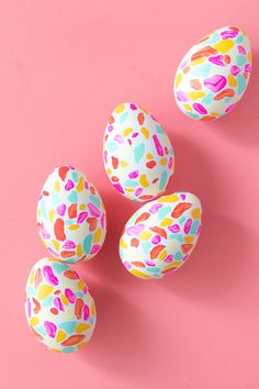 four painted eggs on a pink surface