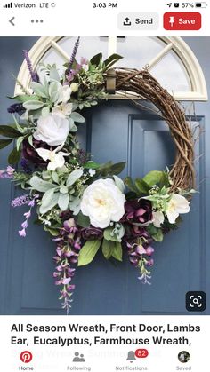 a wreath with flowers and greenery hanging on the front door to welcome people into the house