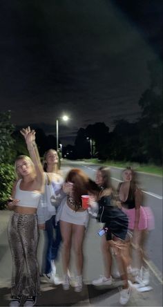 a group of young women standing next to each other on the side of a road