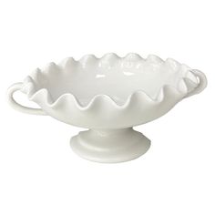 a white bowl on a pedestal with an oval base and scalloped design in the center