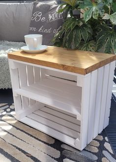 a coffee table made out of pallet wood with a plant in the corner and a cup on top