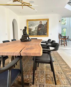 a dining room table with black chairs and a large painting on the wall behind it