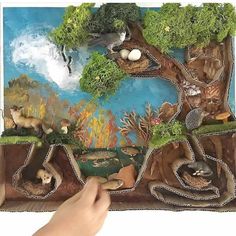 a person is holding up a paper cutout with animals and trees on the bottom