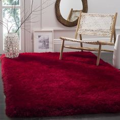 a living room with a red rug on the floor next to a chair and mirror