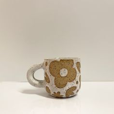 a white and brown coffee cup sitting on top of a table next to a wall