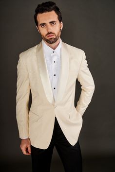 a man in a white tuxedo posing for a photo with his hands on his hips