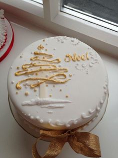 a white cake with gold decorations on it sitting next to a red and white christmas ornament