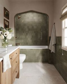 a bath room with a toilet a sink and a bath tub next to a window