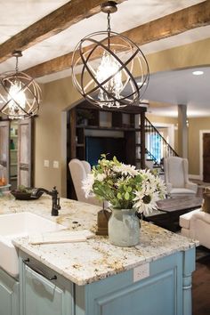 an image of a kitchen island with flowers in the center and chandelier above it