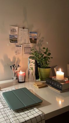 a white desk topped with a laptop computer next to a candle and potted plant