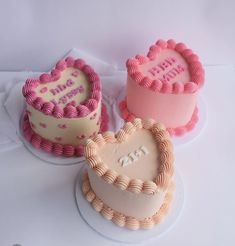 three heart shaped cakes sitting next to each other on top of a white tablecloth