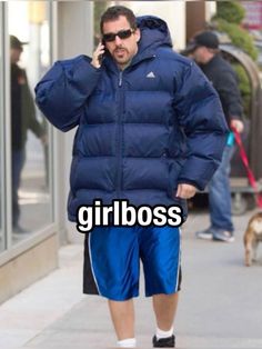 a man walking down the street while talking on a cell phone and wearing a blue puffy jacket