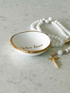 a white beaded bracelet with gold accents and a cross on the side, sitting next to it