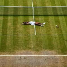 a tennis player laying on the grass with his racquet in front of him