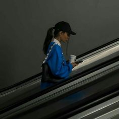 a woman is walking down an escalator with a cup in her hand