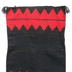 an old black and red rug with fringes on the bottom, in front of a white background