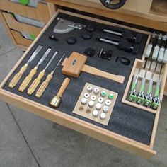 an assortment of tools are displayed in a drawer on the floor next to other items