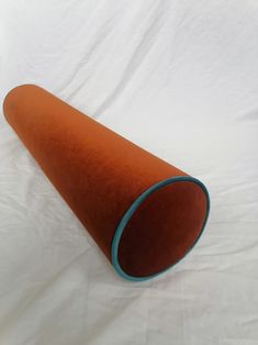 an orange and blue cone shaped object on a white sheeted surface with the top half rolled up