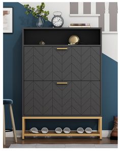 a grey cabinet with gold handles and knobs on it in front of a blue wall