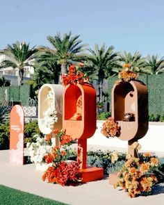 several mailboxes are lined up on the sidewalk near some flowers and palm trees