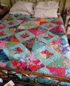 a bed with a colorful quilt on top of it next to a pair of eyeglasses