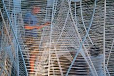 two men are standing in front of large metal structures with wires attached to the sides