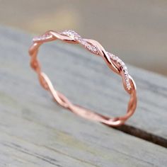 a rose gold wedding band with white diamonds on it, sitting on a wooden surface