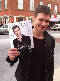 a man holding up a magazine in the street