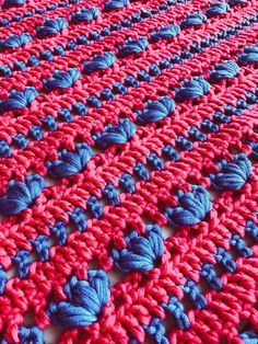 a crocheted red and blue blanket is laying on the floor