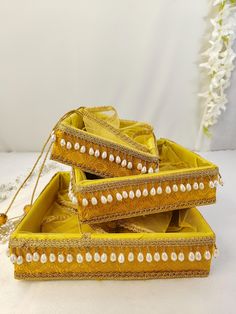 three yellow jewelry boxes with pearls on the sides and bead trimming around them